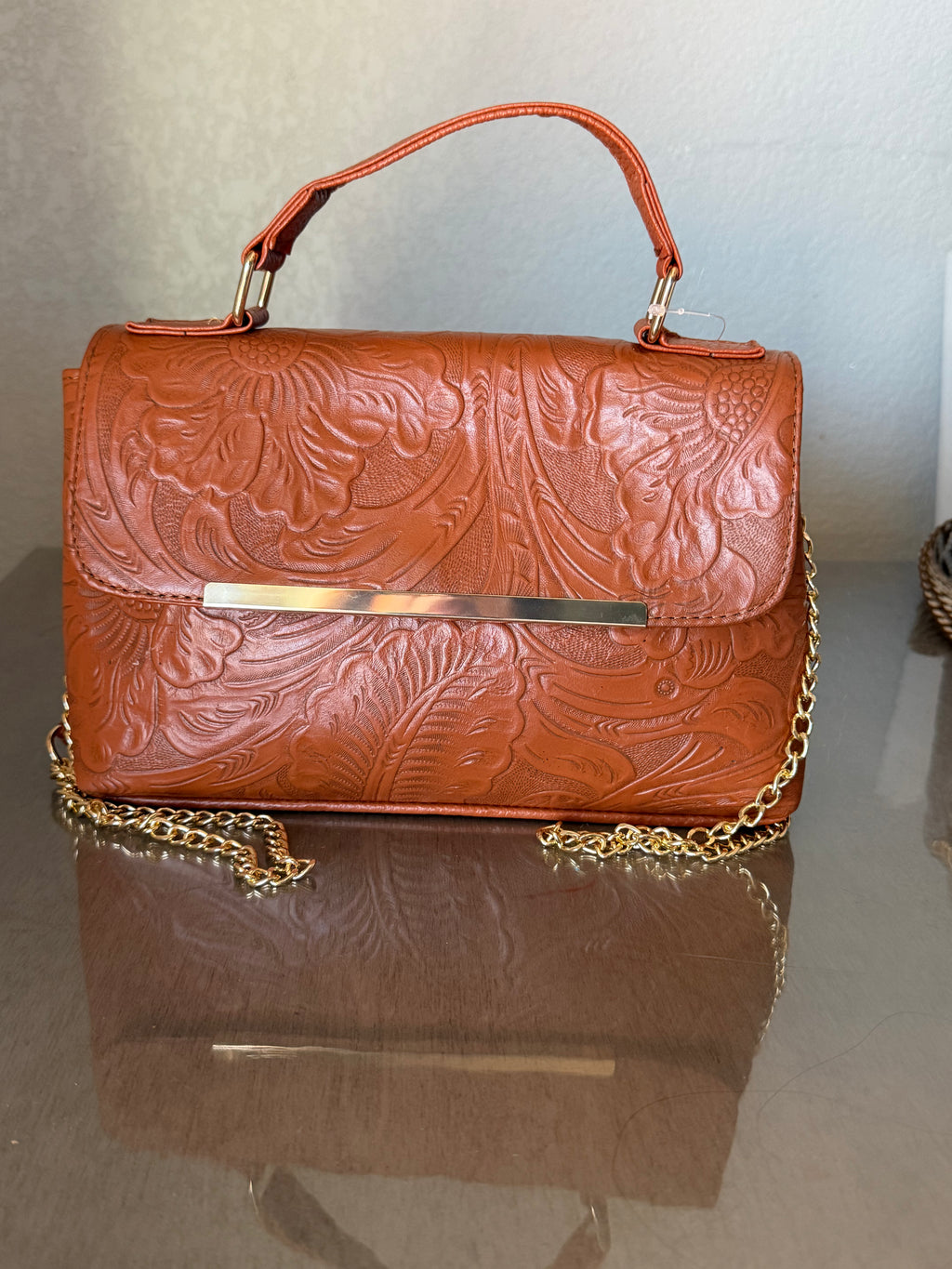 This brown, floral-embossed leather satchel medium gold tooling top handle bag