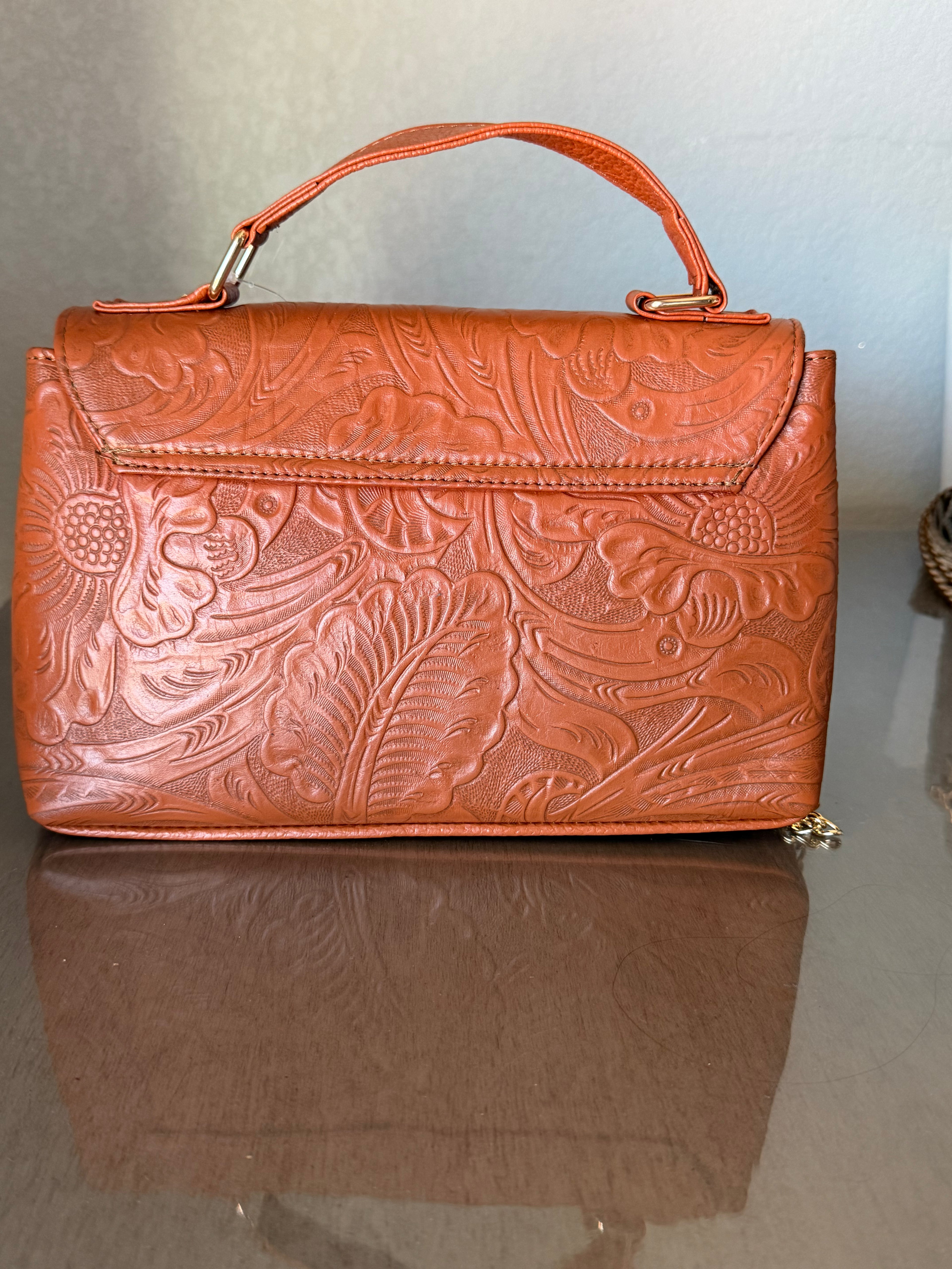 This brown, floral-embossed leather satchel medium gold tooling top handle bag